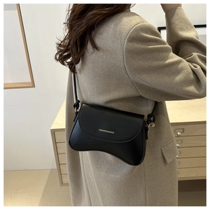 Detailed close-up of a black textured crossbody bag featuring a curved bottom and gold text