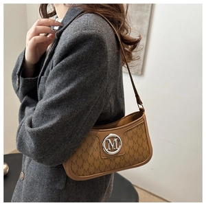 Brown vintage underarm bag with M-letter print shown on a model in a grey suit