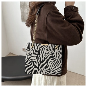 Detail of zebra pattern crossbody bag featuring gold metal chain and leather strap