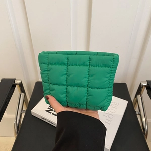 Vibrant green quilted puffy clutch bag made of soft nylon held in hand for daily style