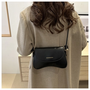 Detailed back view of a black crescent crossbody bag with gold fashion lettering