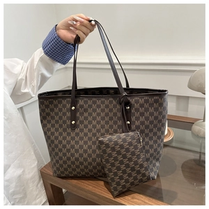 Detail of a brown monogram tote bag and matching pouch with gold rivet hardware