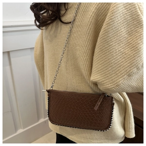 Detail shot of brown woven leather texture with silver bead trim on a chain bag