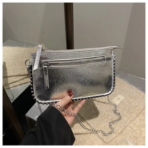 Detail of silver metallic crossbody bag featuring polished studs and chain strap
