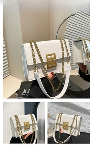 Close-up of white textured leather handbag featuring a bold gold geometric metal lock