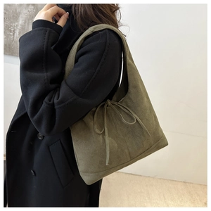 Detail of army green suede tote bag featuring a decorative bow and handle design