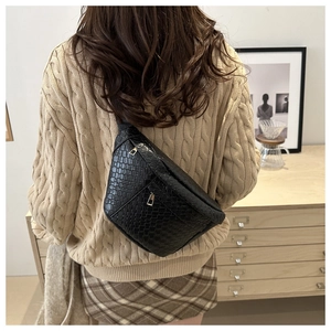 Detail of black faux crocodile leather fanny pack with premium metal zipper on a model