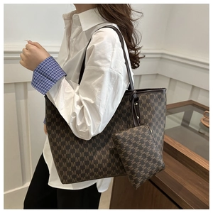 Close-up of the large letter-print tote bag and matching pouch on a model in white shirt