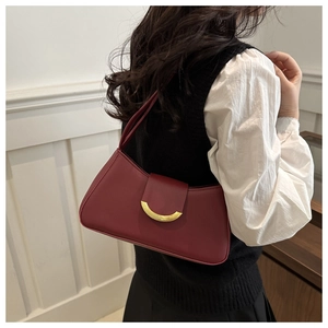 Close-up of a deep red leather underarm bag with an elegant crescent gold buckle