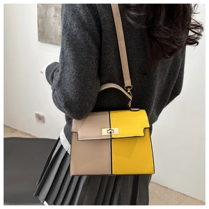 Detail of two-tone crossbody Kelly bag featuring metal twist-lock and shoulder strap