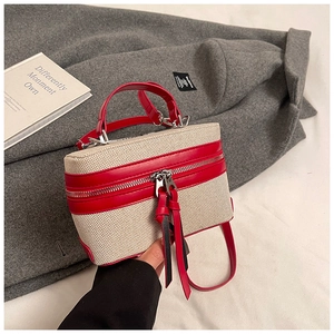 Detail of box bag featuring beige canvas, red leather trim and long tassel zippers