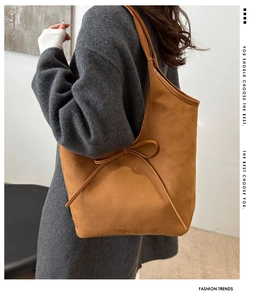 Close-up of brown suede shoulder bag featuring an elegant bow tie knot decoration