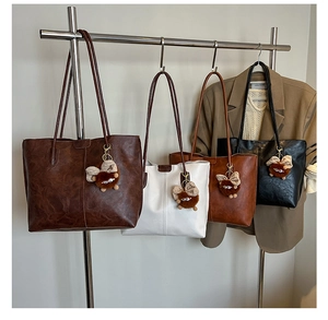 Sacs cabas rétro en similicuir en quatre couleurs avec breloques de sac sur un support