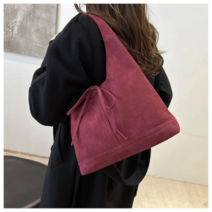 Detail of burgundy faux suede tote bag with elegant bow tie decoration on model