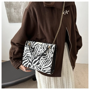 Close-up of zebra pattern handbag featuring a gold chain strap and structured design