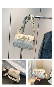 Detail of white cylinder shoulder bag with black lettering and gold logo hardware