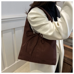 Close-up of a dark brown suede shoulder bag featuring an elegant decorative bow knot detail