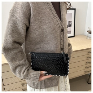 Detail of black woven texture chain bag with silver studs and metal hardware