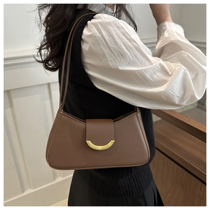 Detail of dark brown leather underarm bag featuring elegant golden crescent buckle