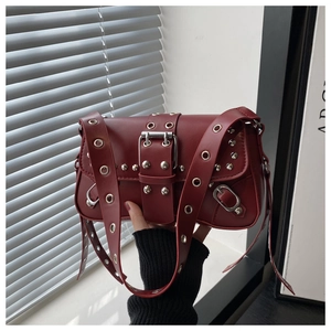 Close-up of deep red leather bag with silver rivets and metal buckle detail