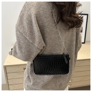 Detail of black woven shoulder bag with silver bead trim and metallic chain strap