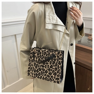 Detail shot of leopard print handbag featuring gold chain strap and leather handle