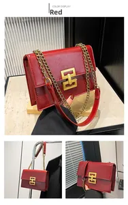 Detail view of red textured leather bag with gold geometric buckle and chain strap