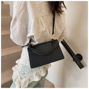 Detail of a black embossed PU leather flap bag featuring clover patterns and gold hardware