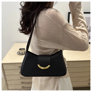 Detail of a chic black leather underarm bag featuring a crescent gold metal buckle on a strap