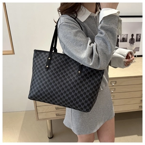 Detail view of large tote bag with grey M-pattern and black straps with gold rivets
