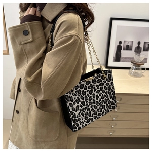Detail of leopard print handbag featuring a gold chain strap in a cozy interior setting
