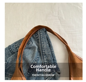 Detail view of large capacity shoulder bag showing brown leather handles and stitching