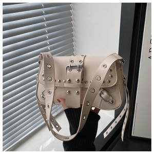 Detail of beige crossbody bag featuring silver studs and oversized metal pin buckle