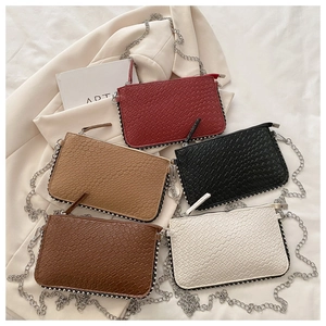 Close-up of five woven texture crossbody bags with silver rivets and metal chain straps