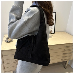 Détail du sac hobo en velours côtelé noir avec texture souple et nœud décoratif