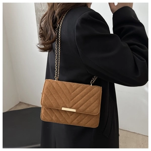 Close-up of brown suede crossbody bag with V-quilted texture and gold chain strap