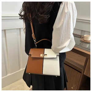 Detailed view of bicolor Kelly bag with golden twist lock and adjustable shoulder strap