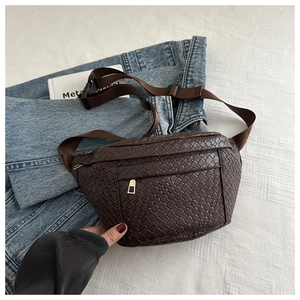 Detail of dark brown woven leather texture on a fashion chest bag with a golden zipper
