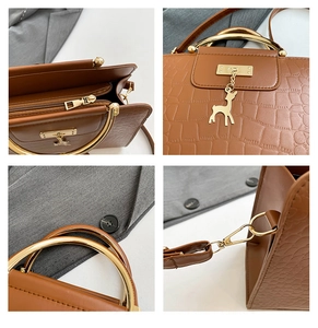 Detail view of brown crocodile texture handbag with gold metal ring handle and deer charm