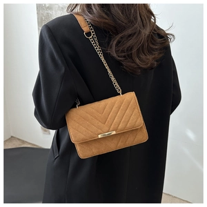 Close-up of brown quilted bag showing V-shape stitching and golden chain strap detail