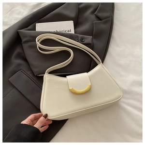 Detail of a creamy beige leather underarm bag with a prominent gold arc buckle