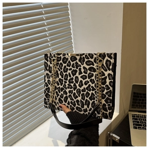 Détail du sac cabas léopard avec bandoulière chaîne dorée et anse en cuir noir