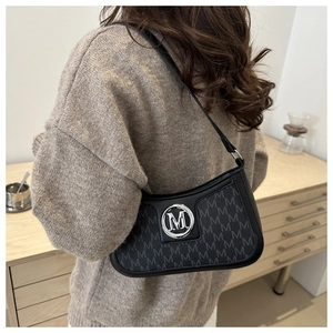 Detail of hobo bag showing silver M logo and monogram pattern on leather surface