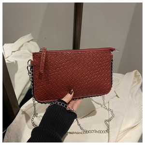 Detail view of woven brick red shoulder bag with silver chain strap and zipper