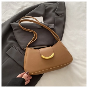 Close-up of a brown underarm bag with a golden crescent buckle on a gray blazer