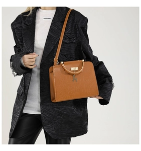 Detail of camel crocodile pattern handbag with gold hardware and metal top handle