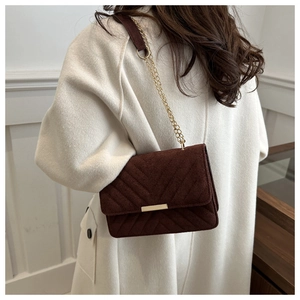 Close-up of brown suede shoulder bag with V-quilted stitching and gold chain strap detail