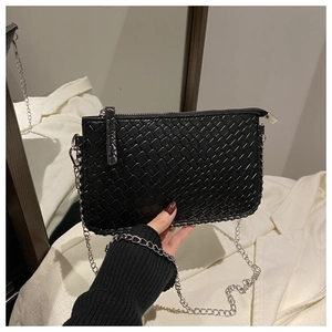 Close-up of black woven leather texture and silver chain strap on crossbody bag