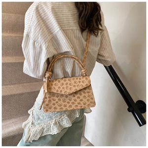 Beigefarbene PU-Leder Handtasche mit Blumenmuster an einer Frau im Treppenhaus