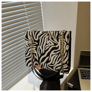 Détail d'un sac cabas zébré avec chaîne en métal doré et bandoulière en cuir